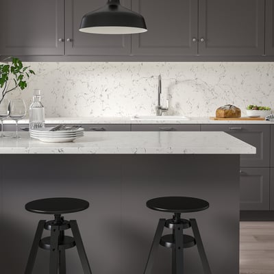 Modern kitchen with TÄRNHULT white marble-patterned counter, dark grey cabinets, black bar stools, and black pendant light.