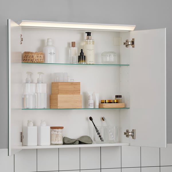 Well-lit cabinet with glass shelves, storing toiletries and bottles, ensuring organised bathroom essentials.