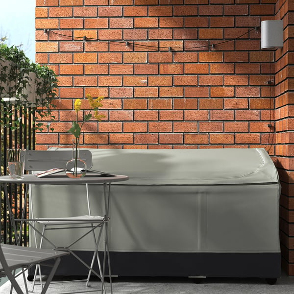 Light grey VÄTTERSÖ storage box on balcony, next to foldable furniture, protects cushions with resistant fabric and ventilation windows.