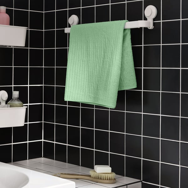 Green VÅGSJÖN towel on white hanger in bathroom.