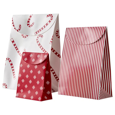 Two festive gift bags: one with red stripes, the other with red snowflakes on white. Brown paper material with string closures.