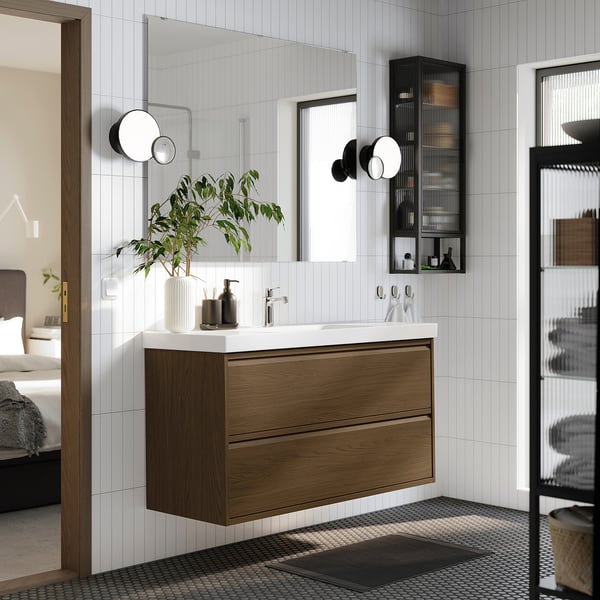 Modern brown oak bathroom cabinet with drawers, white counter, lights, black/white floor, minimalist.