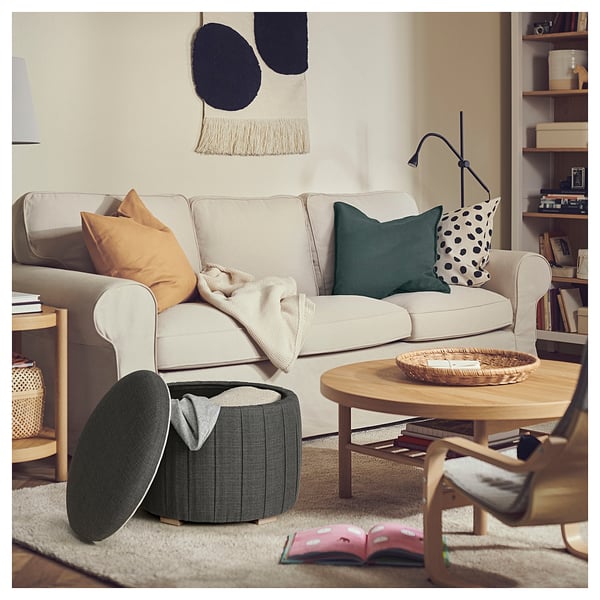 Cosy living room with beige sofa, wooden coffee table, and green storage ottoman. Colourful pillows add warmth.
