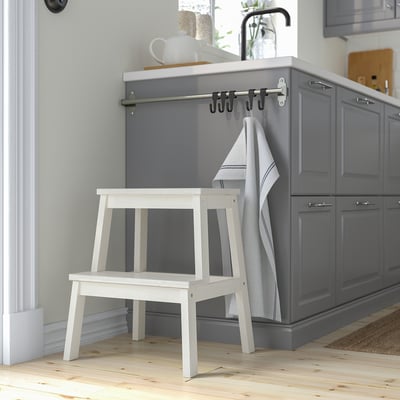 White BEKVÄM stool beside grey cabinets. Compact, stable aspen wood, moves easily.