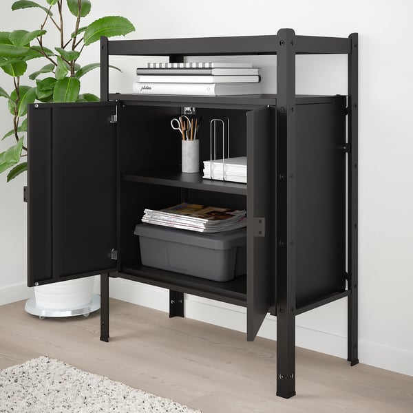 Black metal storage unit with multiple shelves and cabinet, holding books, stationery, and bins.