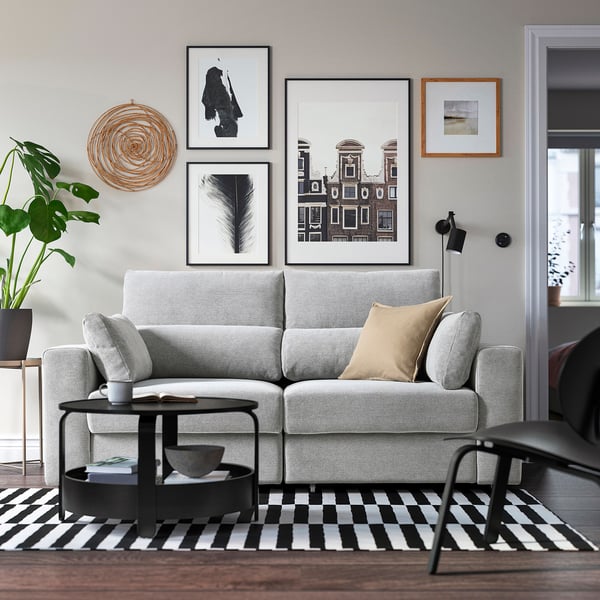 Modern living room with grey sofa, black table, plants, and artwork.