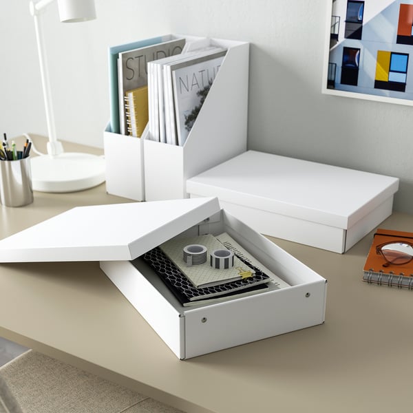 The FJÄDERHARV white box stores files near a workspace, blending neatly with decor, larger than a notebook, made of recycled paper.
