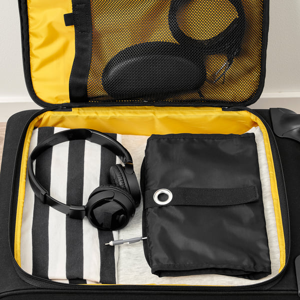 Suitcase open with headphones, a pouch, and a striped cloth tucked inside, showcasing travel organisation.