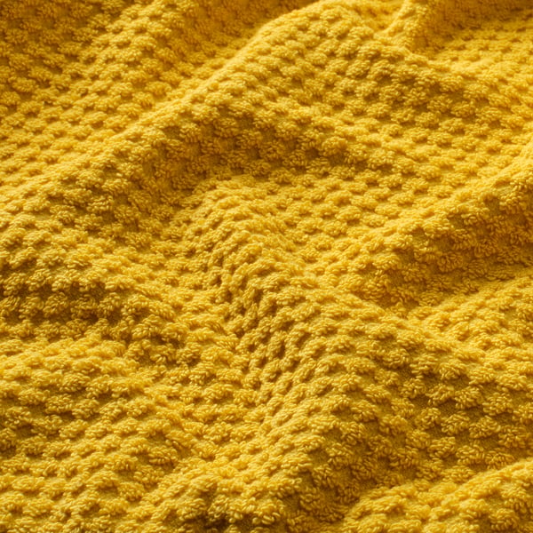 Soft, textured yellow cotton towel close-up, showcasing its fluffy, absorbent quality.