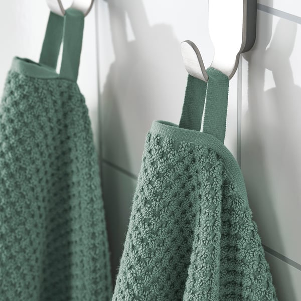 Two green towels hang neatly from hooks, soft texture visible, ideal for absorbent use.