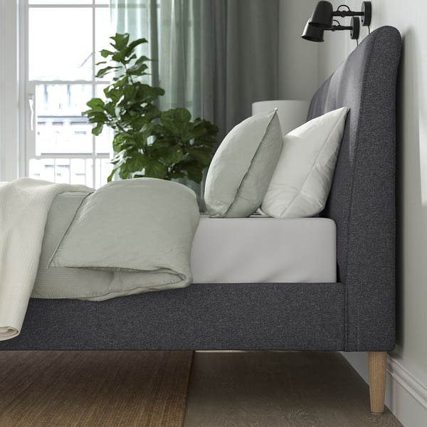 Bed with sloped headboard, soft upholstery, wooden legs, and adjustable bed sides, perfect for reading or resting.