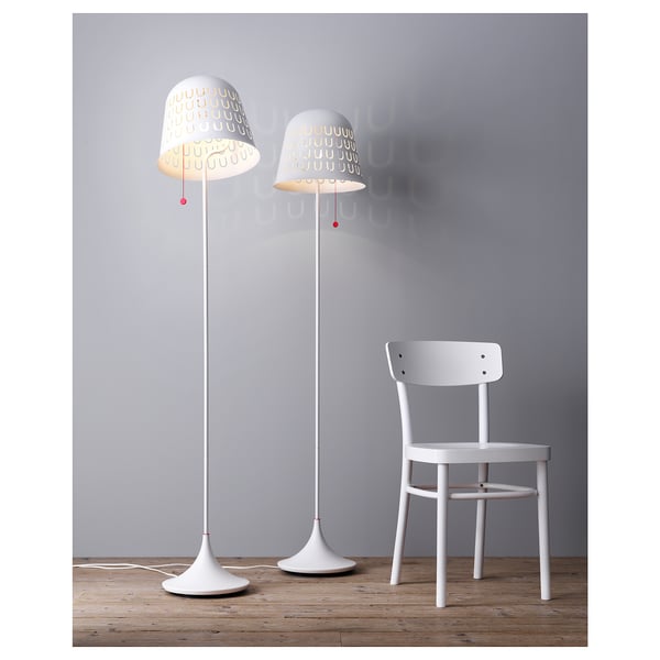 Two modern white floor lamps with patterned shades and a single white wooden chair against a grey wall.