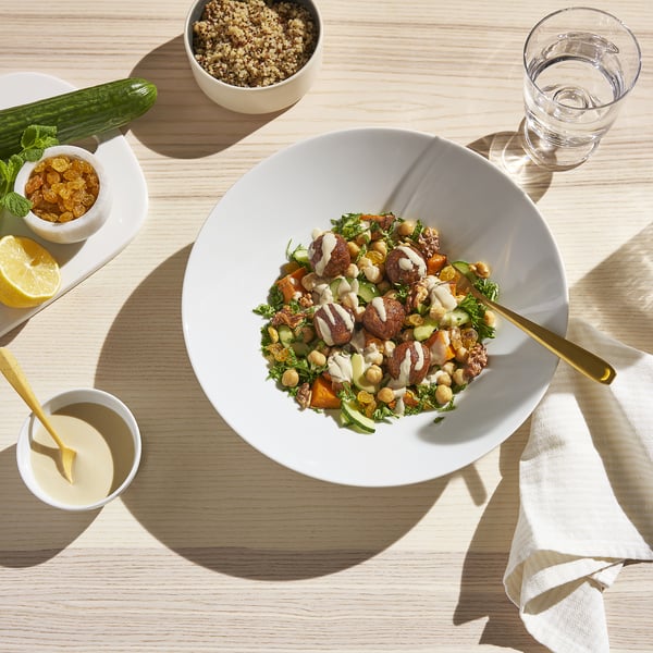 Chickpea salad with sauce, side bowls, glass, cucumber.