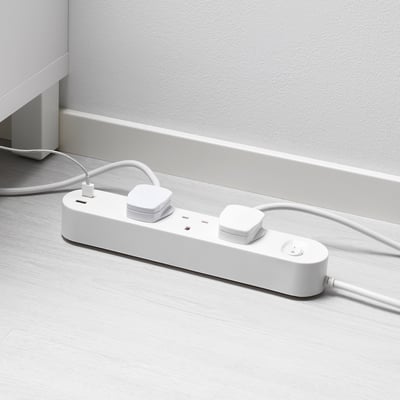 White multi-socket with usb ports on wooden floor. Charges and powers devices efficiently.