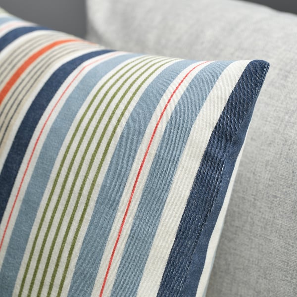 Striped cushion cover on a sofa, multicoloured stripes on blue-gray background, neatly sewn with a zip closure.
