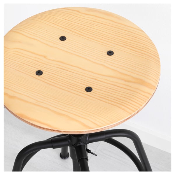 Simple stool with light wood top, three black bolts. Sturdy black metal base, adjustable height.