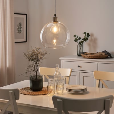 Cosy dining setup with LUNNOM bulb, table decor, beige cloth, chairs, and sideboard with basket.