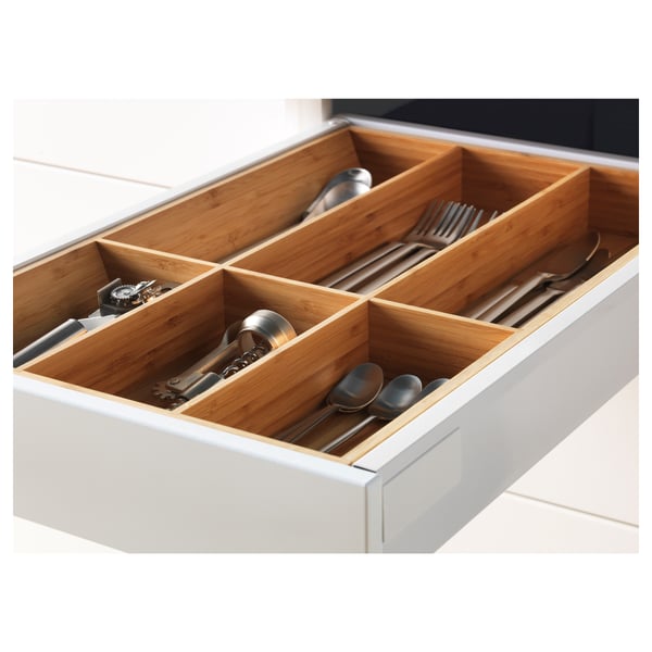 Open kitchen drawer with wooden compartments holding utensils, part of the METOD system.