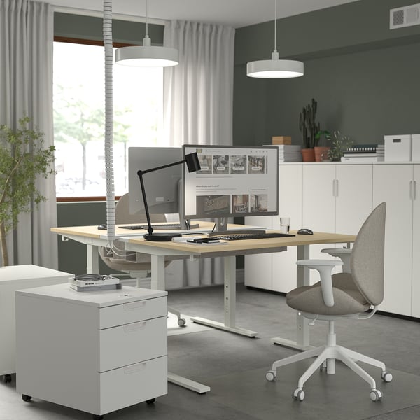 Home office setup with MITTZON adjustable white desk, grey chair, computer, and storage cabinet.