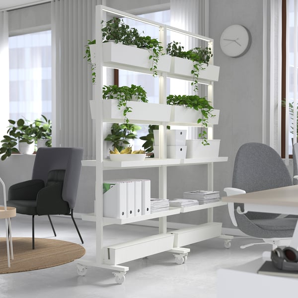 MITTZON white room divider with multiple shelves, holding plants and binders, standing tall beside grey office chairs.
