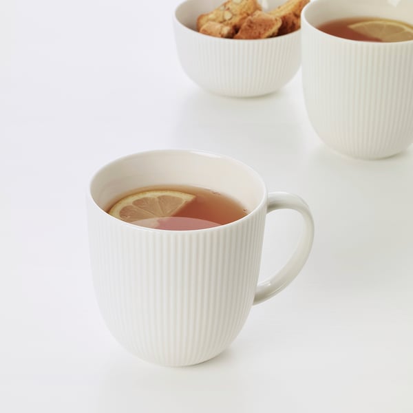Three white mugs with lemon tea; one mug close-up shows lemon slice, suggesting refreshing flavour. Simplistic and elegant design.