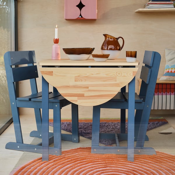 OMMJÄNGE blue pine table with foldable leaves, small, with bowls and pitcher, colourful rug.