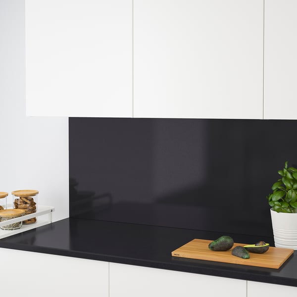 Modern kitchen counter with avocados on cutting board, potted plant, and canisters.