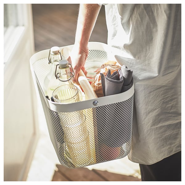Person holding mesh RISATORP basket with compartments.