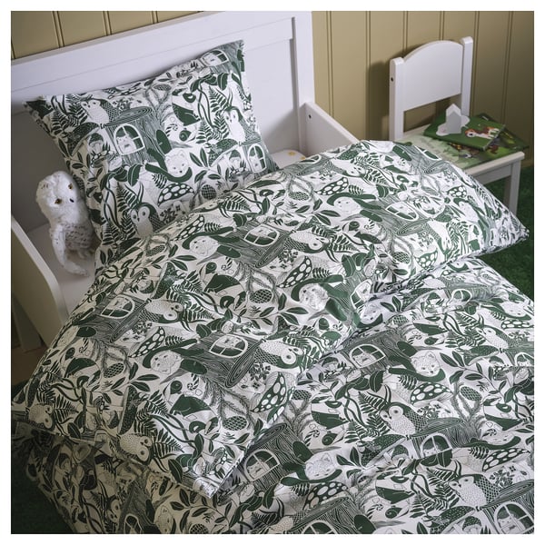 A single bed with SKOGSDUVA duvet, woodland prints, white headboard, chair, and stuffed toy. Cosy forest-themed kids room.