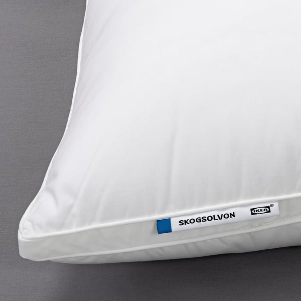 White SKOGSOLVON pillow on a bed, featuring soft, breathable fabric and supportive polyester filling.