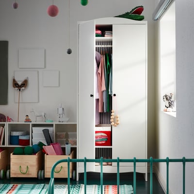 Childrens room with white SMÅGÖRA wardrobe, green railing, wooden boxes, colourful decor, and hanging toys.