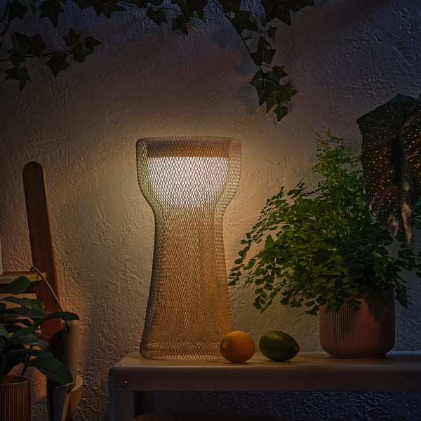 A decorative lamp on a shelf with fruits and plants, emitting a warm glow.