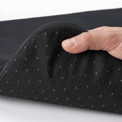 Hand pressing a black, textured STAGGSTARR chair pad, showcasing its removable cover for easy washing.