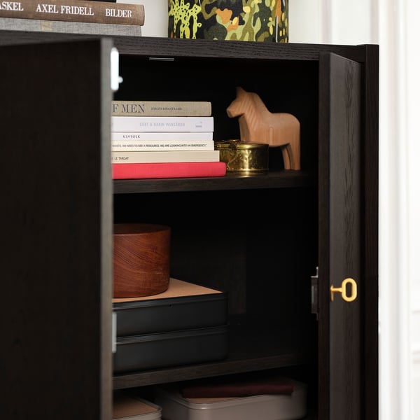 A stylish cabinet with adjustable shelves displaying books and decor. Brass key lock visible on the door.