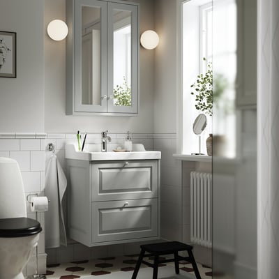 Modern bathroom with grey vanity, chrome fixtures, mirror, white tiles, black floor.