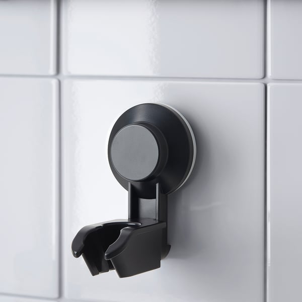 Black suction cup shower bracket on tiled wall. Holds hand shower neatly.