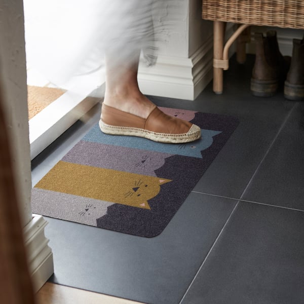 Person steps onto cat-themed TURISTVÄG mat in entryway.
