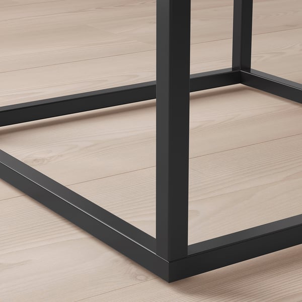 Close-up of modern tables sturdy, black metal legs and light wood surface, showcasing sleek design and quality materials.