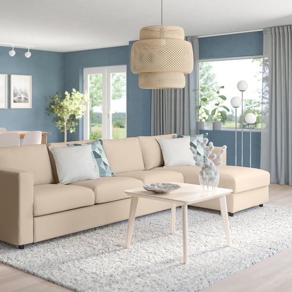 Modern living room: beige VIMLE sectional sofa, white coffee table, large window, blue walls, light fixtures, rug, and decorative accents.