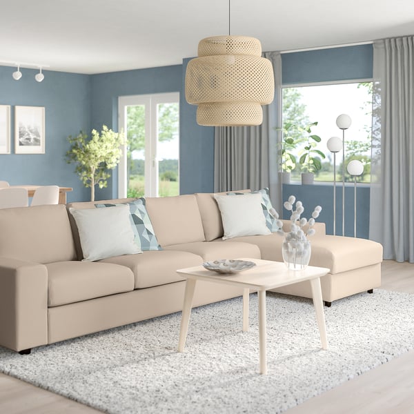 Modern living room: beige VIMLE sectional sofa with white cushions, white coffee table, white rug, blue walls, large window, and pendant light.