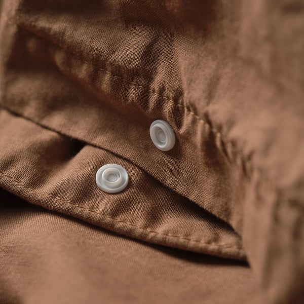 Close-up of brown duvet cover with two white buttons.