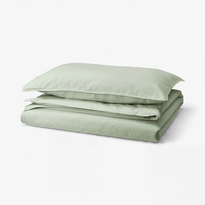 A stack of soft green bedding: two pillows and a folded duvet, all neatly arranged, displaying light green colour and smooth cotton texture.