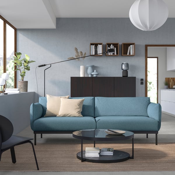 Modern living room a blue ÄPPLARYD sofa with beige cushions, round coffee table, and sleek decor.