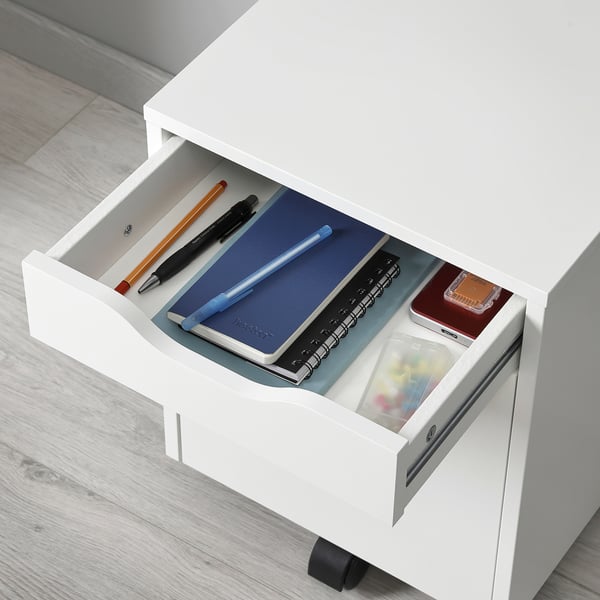 Open white drawer unit displaying various stationery items: pens, pencils, notepad, ruler, and small containers. Ideal for desk organisation.