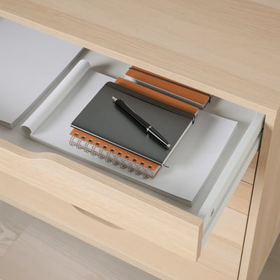 Desk drawer with notebook, pen, and paper roll, showcasing organised workspace with ALEX unit.