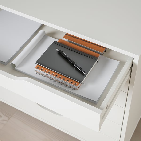 White desk drawer with notebook, pen, and notepad, showing storage and organisation for office supplies.