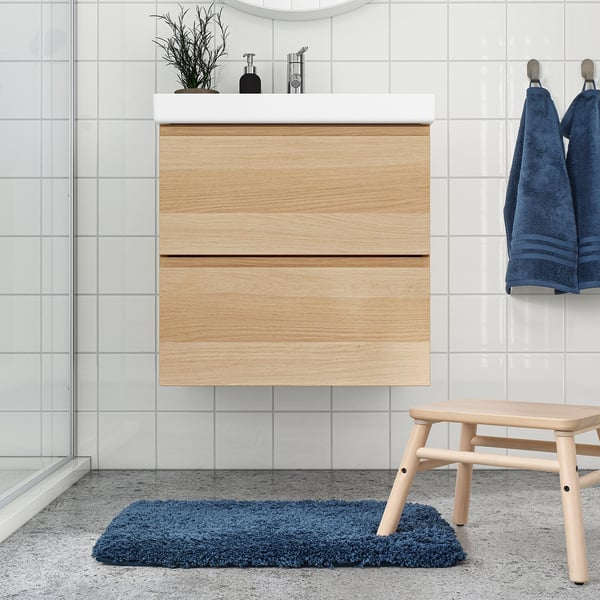 Modern bathroom with wooden vanity, mirror, blue towels, and ALMTJÄRN mat.