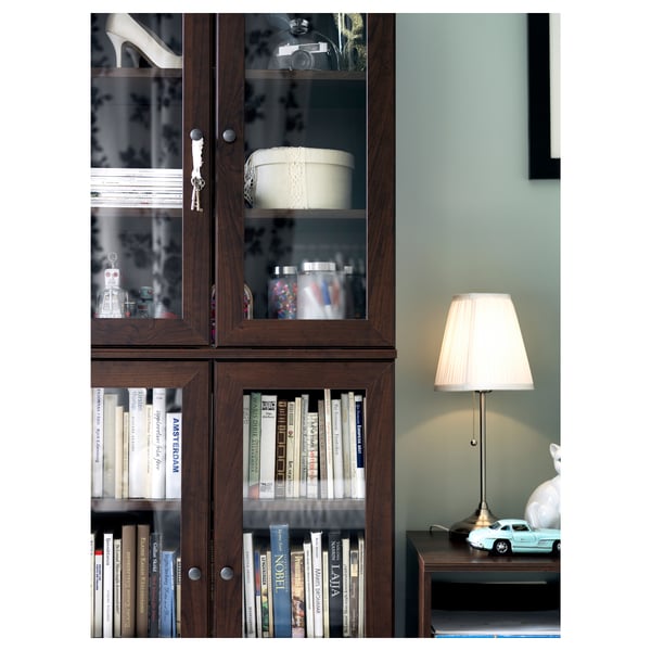 Bookshelf with books & decor, lamp, green wall.