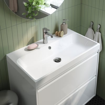Modern bathroom sink with marble basin, tap, soap, brush, and mirror. Crisp edges, clean design, and integrated storage space.