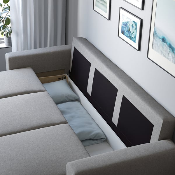 Grey sofa-bed with cushions converted to bed, showcasing storage space underneath.